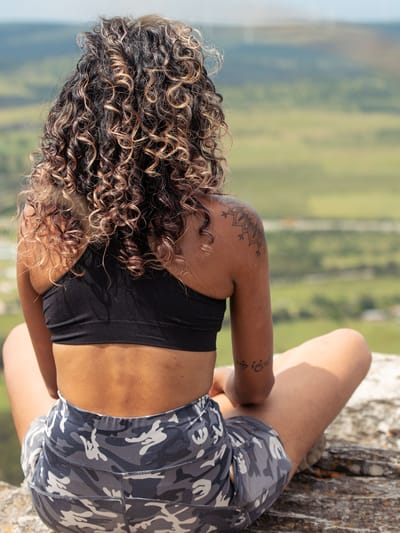 woman sitting on a rock in contemplation as she engages in an RV gratitude challenge as a digital nomad vanlifer